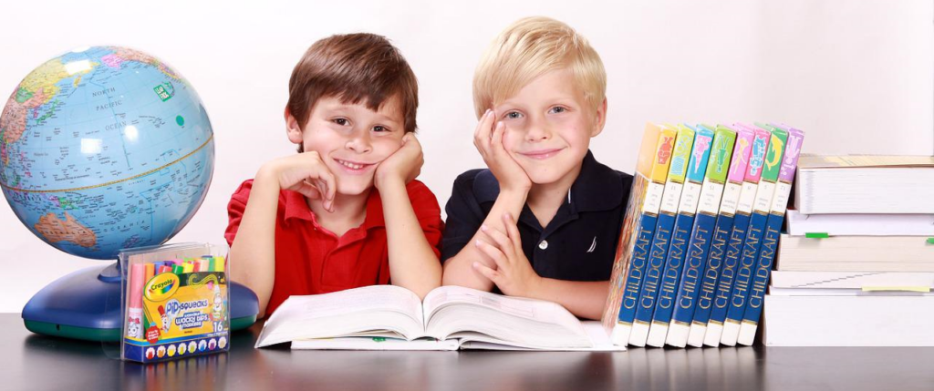 two children reading a text book in the library